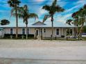 A light beige home with white trim and a large front yard, under a bright sky at 821 E 1St Ave, New Smyrna Beach, FL 32169