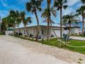 A coastal home with a light beige exterior, palm trees, and a gravel driveway at 821 E 1St Ave, New Smyrna Beach, FL 32169