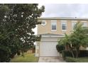 Tan two-story house with white garage door and landscaping at 13653 Daniels Landing Cir, Winter Garden, FL 34787