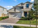 Two-story house with beige exterior, two-car garage, and landscaping at 2928 Muller Oak Loop, Ocoee, FL 34761