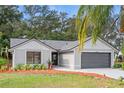 Newly renovated home exterior features a gray and white color scheme, landscaping, and a two-car garage at 1395 Kenneth Ave, Casselberry, FL 32707