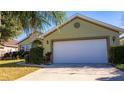 Green house with white garage door, landscaping, and a paved driveway at 5649 Magnolia Bloom Ter, Oviedo, FL 32765