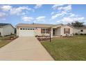 Tan single-story house with a landscaped lawn and attached garage at 3405 Forsythe Ter, The Villages, FL 32162