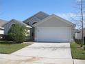 Front view of a single-story house with a white garage door and manicured lawn at 603 Keppel Ct, Kissimmee, FL 34746