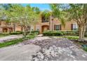 Two-story townhome with a landscaped front yard, brick paver driveway, and palm trees at 120 Palermo St, Davenport, FL 33897