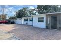 White house with teal accents, brick paver driveway, and modern entryway at 5958 Lawnview Dr, Orlando, FL 32812