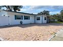 White house with teal accents, brick paver driveway, and fenced yard at 5958 Lawnview Dr, Orlando, FL 32812