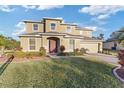 Two-story house with a red door, landscaping, and a paved driveway at 11113 Scenic Vista Dr, Clermont, FL 34711