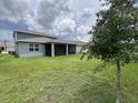 Expansive backyard featuring a covered patio, lush green grass, and a young tree, ideal for outdoor enjoyment at 4535 Gliding Wave St, Winter Garden, FL 34787
