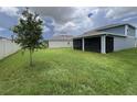 Wide backyard featuring a covered patio, lush green grass, and a young tree next to a fence at 4535 Gliding Wave St, Winter Garden, FL 34787