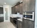 A modern kitchen featuring a stainless steel oven, marble counters and dark wood cabinets at 9819 Gobat Aly, Orlando, FL 32827