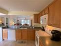 Kitchen with wood cabinets, appliances, and view to living area at 2530 Saffron Ln, The Villages, FL 32162