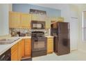 Kitchen with light wood cabinets, black appliances, and a mosaic backsplash at 2740 Coupe St, Kissimmee, FL 34746