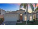 Tan house with a two-car garage, palm tree, and manicured lawn at 8030 King Palm Cir, Kissimmee, FL 34747