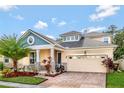 Two-story house with a light yellow exterior, a two-car garage, and palm trees at 2487 Empress Dr, Kissimmee, FL 34741