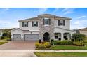 Two-story house featuring stonework and a three-car garage at 16750 Sanctuary Dr, Winter Garden, FL 34787