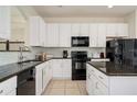 Modern kitchen with white cabinets, granite counters, and black appliances at 2641 Tranquility Way, Kissimmee, FL 34746