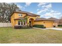 Two-story house, yellow exterior, landscaping, and a two-car garage at 10820 Wyandotte Dr, Clermont, FL 34711