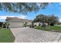 House exterior showcasing a brick paver driveway and lush landscaping at 2039 Palo Alto Ave, The Villages, FL 32159