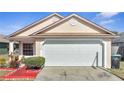 Tan house with white garage door, red walkway, and landscaping at 6433 Livewood Oaks Dr, Orlando, FL 32818