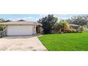 Front view of house with stone exterior, attached garage, and large lawn at 1429 Royal Palm Dr, Edgewater, FL 32132