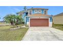 Two-story house with brown garage door and landscaping at 1001 Dampierre Ct, Kissimmee, FL 34759