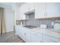 White kitchen cabinets, gas cooktop, and gray hexagon backsplash at 1987 Key Bay Trl, Kissimmee, FL 34747