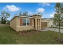 Tan house with brown garage door, landscaping, and paved driveway at 1244 White Ash Loop, Deland, FL 32720