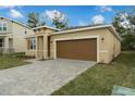 Tan house with brown garage door, landscaping, and paved driveway at 1244 White Ash Loop, Deland, FL 32720