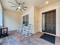 Cozy front porch featuring rocking chairs, ceiling fan, and a patterned brick floor at 190 Crepe Myrtle Dr, Groveland, FL 34736