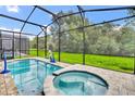 Private screened pool and hot tub with paver deck and grassy backyard at 1919 Tropical Palms Cir, Kissimmee, FL 34747