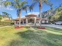 Beautiful home with palm trees, red flowers, and a well-manicured lawn at 3415 S Mellonville Ave, Sanford, FL 32773