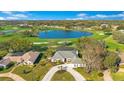 Expansive aerial view of a beautiful home on a lush green golf course near a tranquil lake and blue skies at 8513 Bay Hill Blvd, Orlando, FL 32819