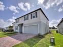 Two-story house with gray siding, gray door, and brick paver driveway at 5305 Maddie Dr, Haines City, FL 33844