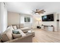 Modern living room with L-shaped sofa, large TV, and ceiling fan at 1260 Lake Helen Osteen Rd, Lake Helen, FL 32744