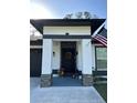 Charming home entrance featuring a decorated black door with stone accents and fresh pink flowers at 1490 11Th Ave, Deland, FL 32724