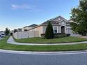 Side view of a house with a gray exterior, white vinyl fence, and lush green landscaping at 3333 Wauseon Dr, Saint Cloud, FL 34772