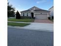 Gray house with a two-car garage, brick driveway, and neatly landscaped front yard at 3333 Wauseon Dr, Saint Cloud, FL 34772