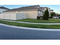 Side view of a house with a gray exterior, white vinyl fence, and neatly trimmed lawn at 3333 Wauseon Dr, Saint Cloud, FL 34772