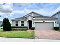 Charming home with manicured lawn, lush landscaping, and a brick paver driveway leading to a two-car garage at 3333 Wauseon Dr, St Cloud, FL 34772