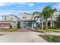 Two-story house with gray siding, teal garage door, and landscaped yard at 671 Bloom Ter, Davenport, FL 33837