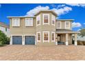 Two-story house with tan exterior, gray doors, and paver driveway at 7697 Fairfax Dr, Kissimmee, FL 34747