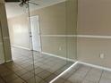 Living room with tile floors, mirrored wall, and door to hallway at 950 Lake Destiny Rd # E, Altamonte Springs, FL 32714