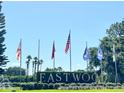 Eastwood entrance sign with flags, lush landscaping, and palm trees at 142 Winghurst Blvd, Orlando, FL 32828