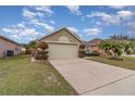 Tan house with a two-car garage and lush green landscaping at 2368 Monaco Cove Cir, Orlando, FL 32825