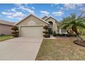 Two-car garage, tan house with landscaping and palm tree at 2368 Monaco Cove Cir, Orlando, FL 32825