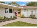 Welcoming front entrance with a bright yellow door, landscaping, and a curved walkway at 332 Lake Winnemissett Dr, Deland, FL 32724