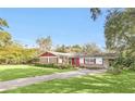 Ranch style home with red exterior and lush green lawn at 5217 N Apopka Vineland Rd, Orlando, FL 32818