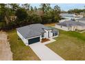 Aerial view of a modern one-story home, showcasing its well-manicured lawn, stylish roof, and concrete driveway at 6579 Sw 132Nd St, Ocala, FL 34473