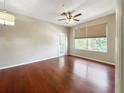An open living room with gleaming hardwood floors, ceiling fan, and sun-filled windows at 13536 Turtle Marsh Loop # 538, Orlando, FL 32837